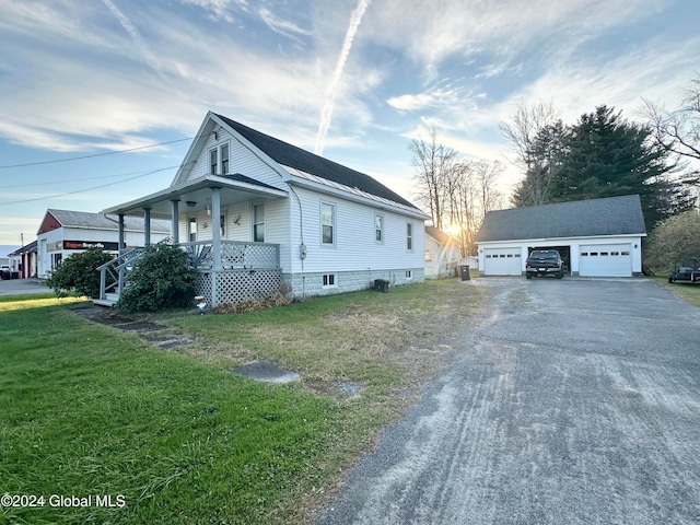 view of property exterior with an outbuilding, a yard, a garage, and covered porch