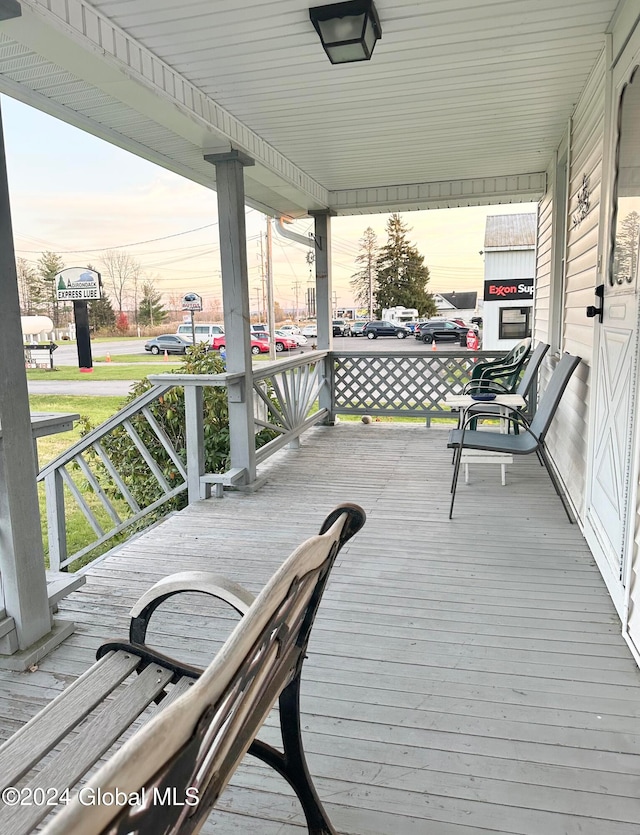 deck at dusk featuring a porch