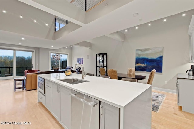 kitchen featuring white cabinetry, sink, light hardwood / wood-style flooring, a center island with sink, and appliances with stainless steel finishes