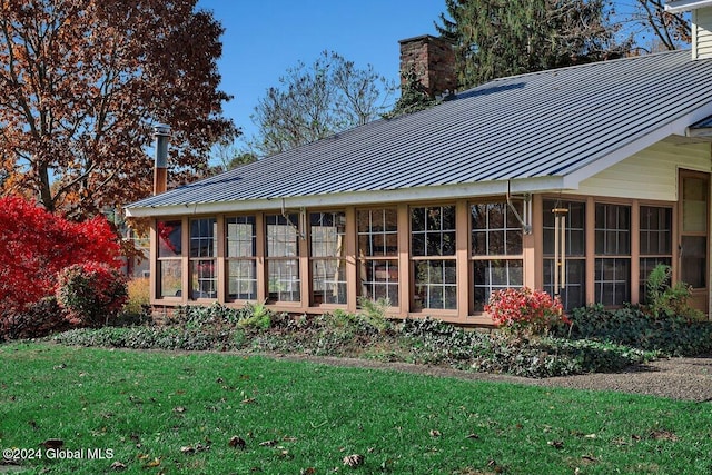 back of property featuring a sunroom and a lawn