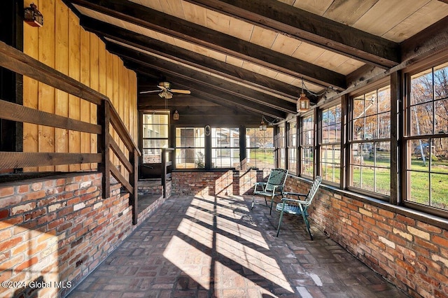 unfurnished sunroom featuring vaulted ceiling with beams, wood ceiling, a healthy amount of sunlight, and ceiling fan