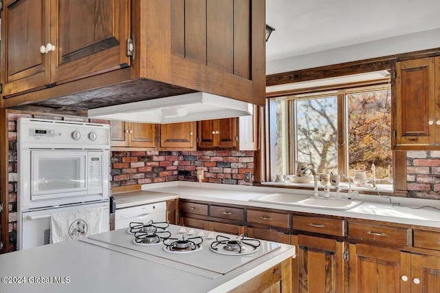 kitchen with premium range hood, tasteful backsplash, sink, and double oven