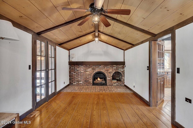 unfurnished living room with ceiling fan, wooden ceiling, light wood-type flooring, a brick fireplace, and lofted ceiling with beams