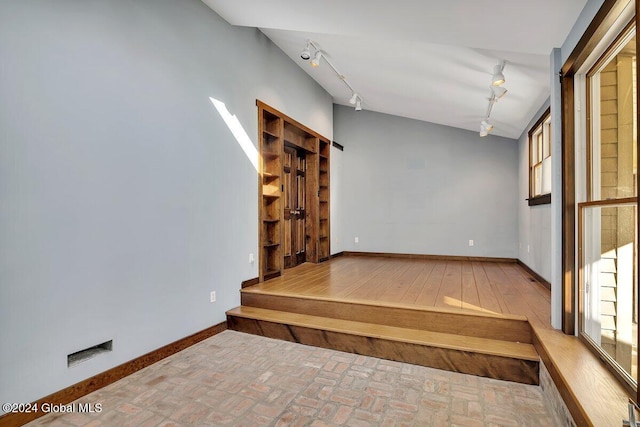 empty room featuring lofted ceiling and track lighting