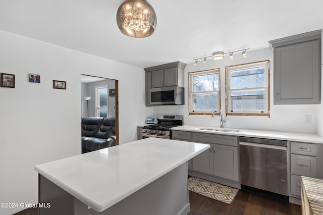 kitchen featuring hanging light fixtures, appliances with stainless steel finishes, dark hardwood / wood-style floors, gray cabinetry, and sink