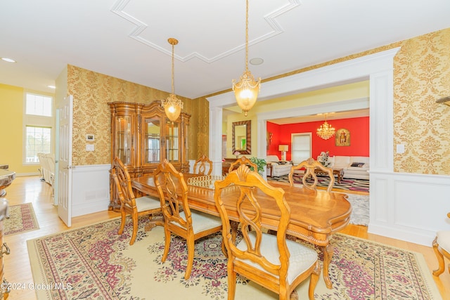 dining area featuring an inviting chandelier, decorative columns, and light hardwood / wood-style floors