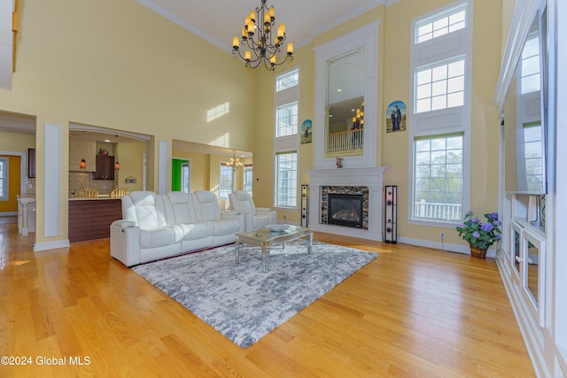 living room with an inviting chandelier, a high ceiling, and light hardwood / wood-style floors