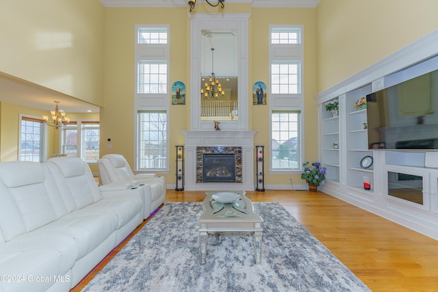 living room with a wealth of natural light, a high end fireplace, a chandelier, and hardwood / wood-style flooring