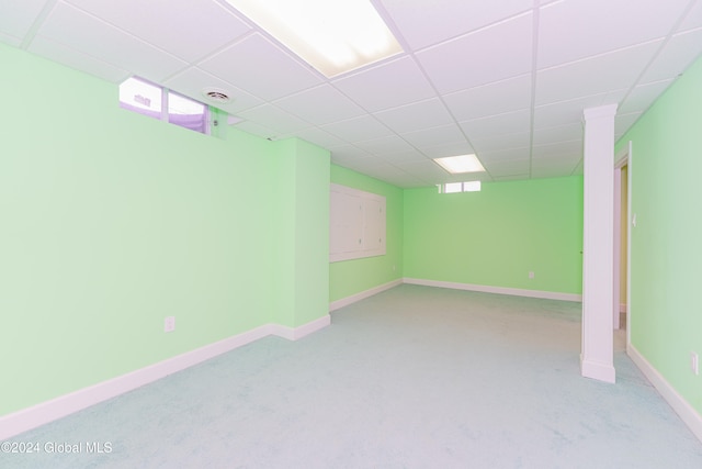 basement featuring a paneled ceiling and light colored carpet