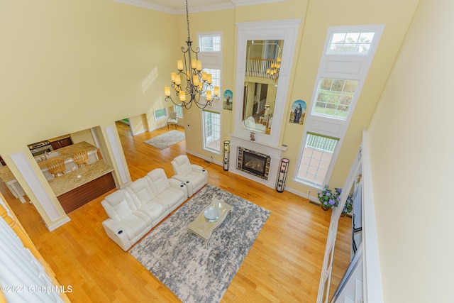 living room featuring an inviting chandelier, ornamental molding, hardwood / wood-style floors, and a towering ceiling