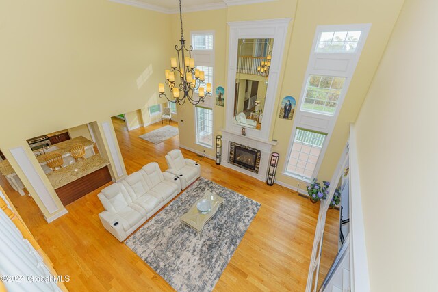 5 Teasdale Ct, Colonie, NY 12189 - living area with a notable chandelier, a glass covered fireplace, wood finished floors, and a towering ceiling