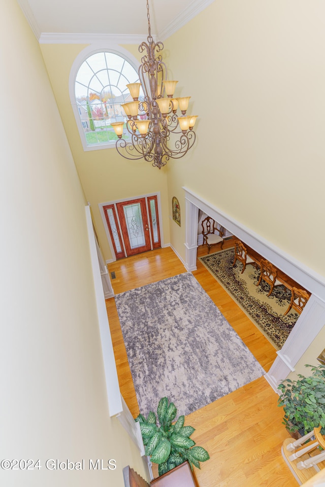 entrance foyer featuring ornamental molding, a chandelier, and hardwood / wood-style flooring