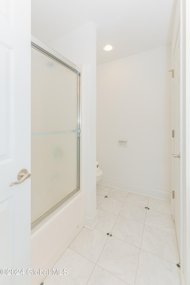 bathroom featuring toilet, shower / bath combination with glass door, and tile patterned flooring