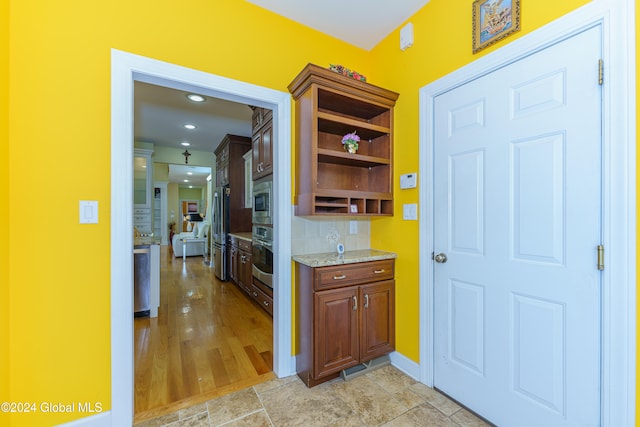 kitchen with light stone countertops, appliances with stainless steel finishes, and light hardwood / wood-style flooring