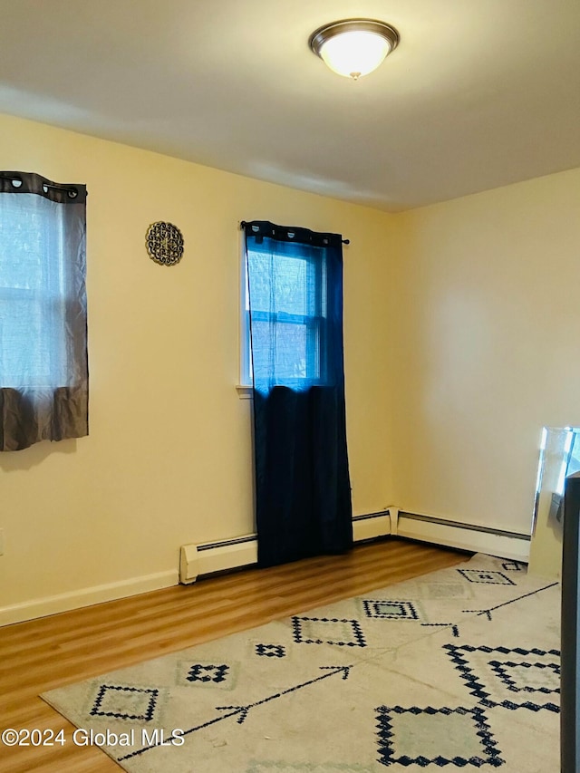 empty room featuring a baseboard radiator and hardwood / wood-style floors