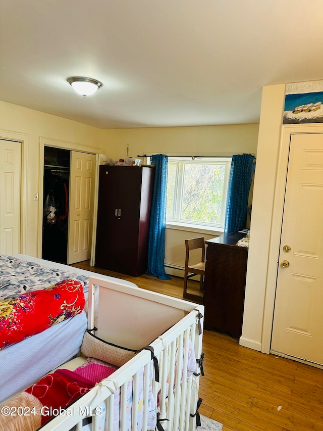 bedroom featuring a closet, hardwood / wood-style floors, and baseboard heating