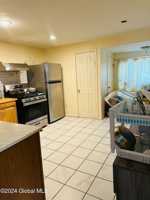 kitchen with ventilation hood, stainless steel range, decorative backsplash, and light tile patterned floors