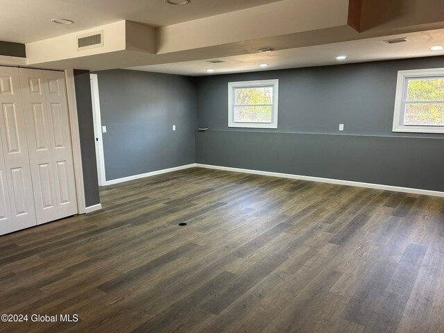 basement featuring a wealth of natural light and dark hardwood / wood-style flooring