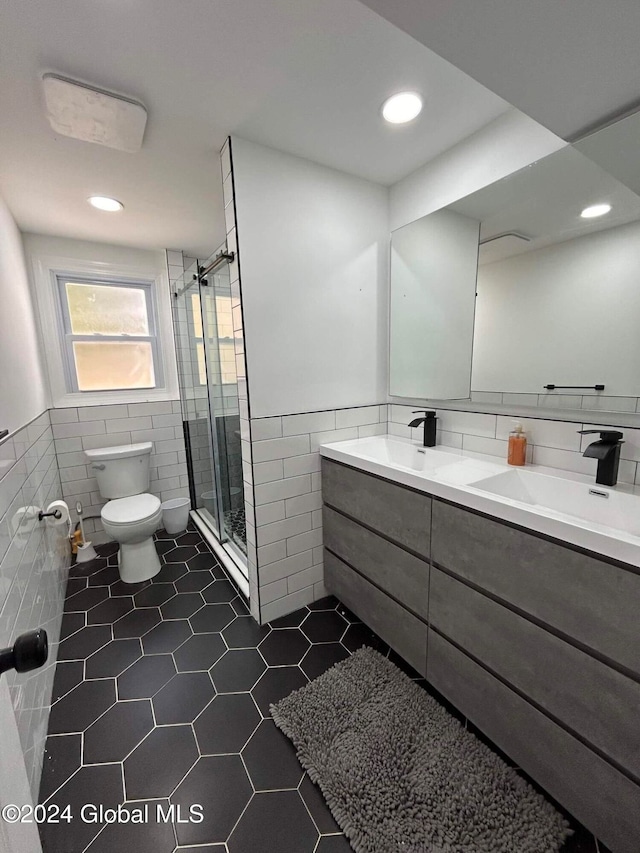 bathroom featuring tile patterned floors, toilet, vanity, tile walls, and an enclosed shower