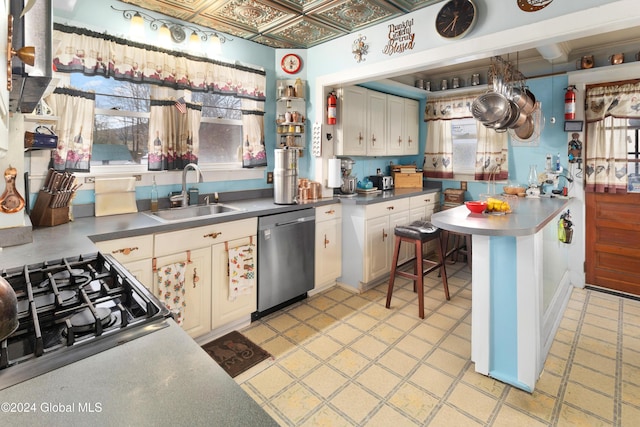 kitchen featuring range, white cabinetry, stainless steel dishwasher, and sink