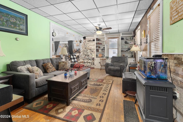 living room featuring a paneled ceiling, ceiling fan, built in features, and light wood-type flooring