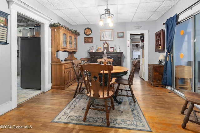 dining space with a chandelier, light hardwood / wood-style flooring, and a drop ceiling