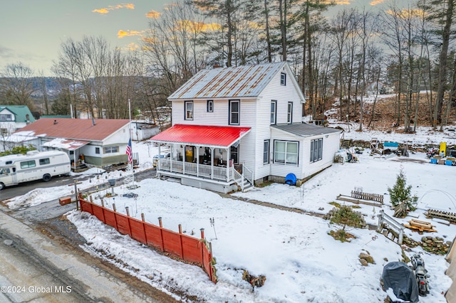 snow covered rear of property featuring covered porch