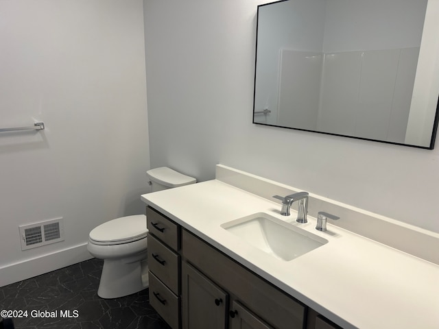 bathroom with toilet, vanity, and tile patterned floors