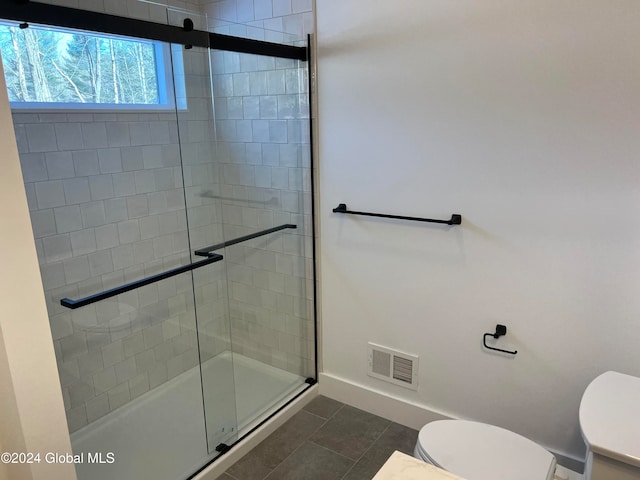 bathroom featuring toilet, tile patterned floors, and walk in shower