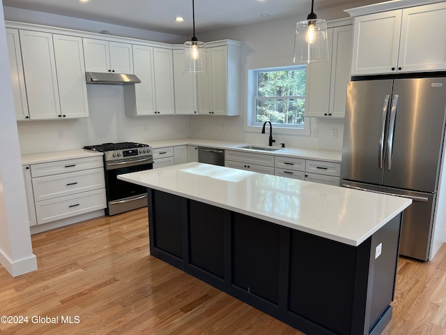 kitchen featuring hanging light fixtures, stainless steel appliances, sink, a center island, and light wood-type flooring