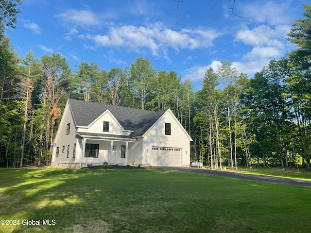 view of front of home featuring a porch, a front lawn, and a garage