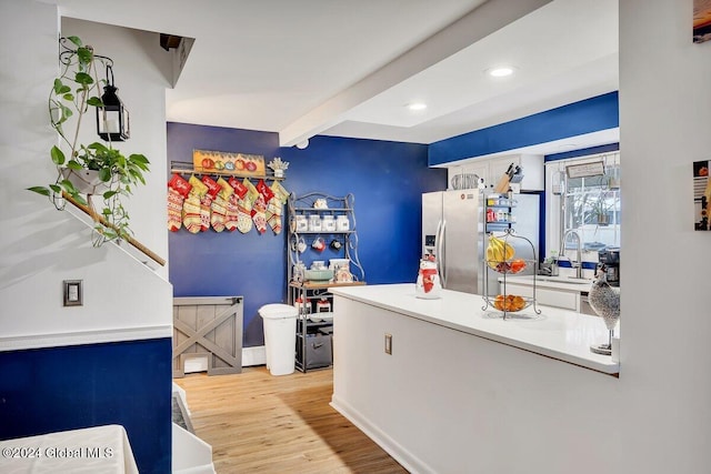 kitchen with beam ceiling, light hardwood / wood-style flooring, and stainless steel refrigerator with ice dispenser