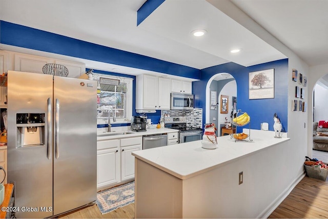 15 Windcrest Dr, Fort Edward, NY 12828 - kitchen featuring stainless steel appliances, arched walkways, light wood-type flooring, white cabinetry, and tasteful backsplash