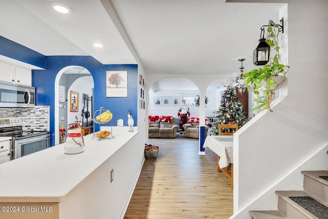 15 Windcrest Dr, Fort Edward, NY 12828 - kitchen featuring appliances with stainless steel finishes, light wood-style floors, arched walkways, white cabinets, and decorative backsplash