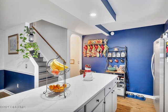 kitchen featuring light stone countertops, stainless steel refrigerator, and light hardwood / wood-style flooring