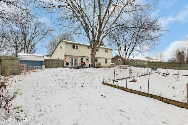 snow covered rear of property featuring french doors