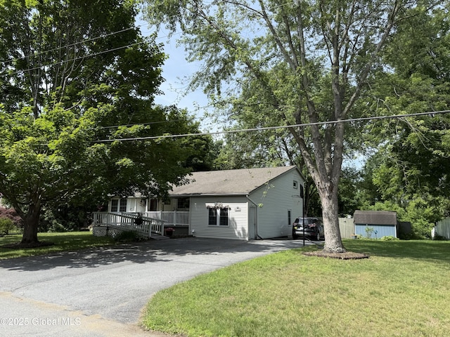 15 Windcrest Dr, Fort Edward, NY 12828 - view of front of property with a storage shed, asphalt driveway, a front yard, a porch, and roof with shingles