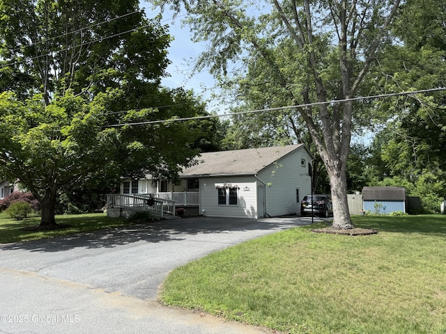 15 Windcrest Dr, Fort Edward, NY 12828 - view of front of house with a storage unit, driveway, a front yard, a shingled roof, and view of scattered trees