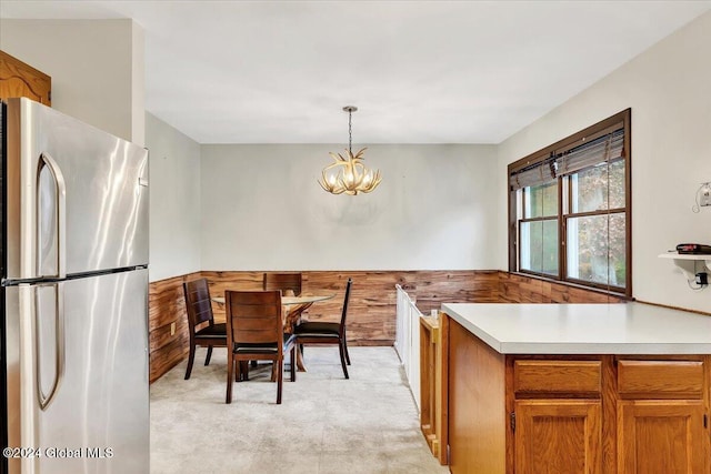 dining room with a notable chandelier, light carpet, and wood walls