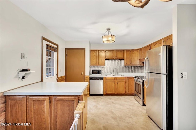 kitchen with decorative backsplash, kitchen peninsula, sink, decorative light fixtures, and appliances with stainless steel finishes