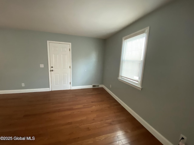 spare room with baseboards, visible vents, and wood finished floors