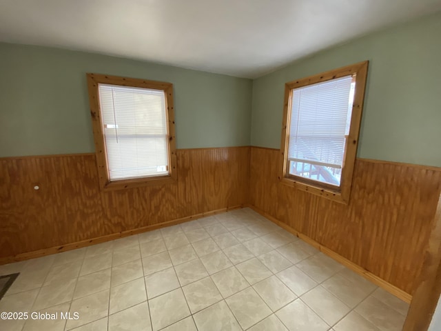 unfurnished room featuring wainscoting and wood walls