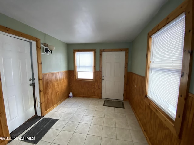 foyer entrance featuring a wainscoted wall, wooden walls, and light tile patterned flooring