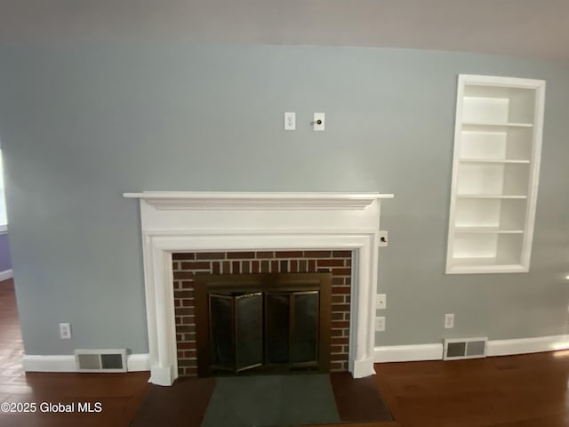 interior details featuring visible vents, a fireplace, baseboards, and wood finished floors