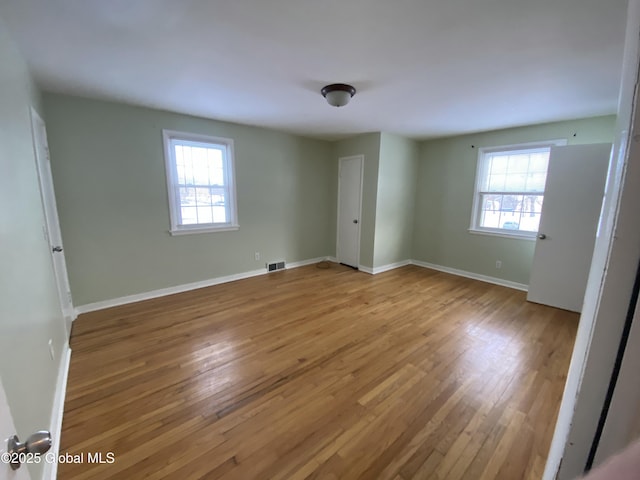 unfurnished bedroom featuring baseboards, visible vents, and hardwood / wood-style floors