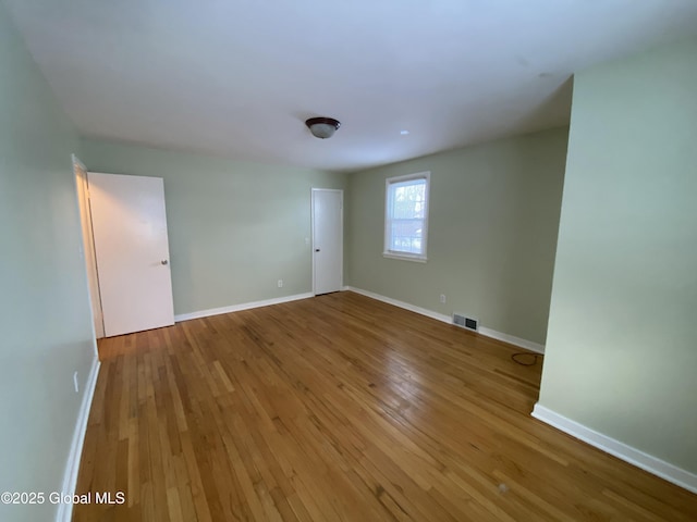 spare room with baseboards, visible vents, and hardwood / wood-style floors