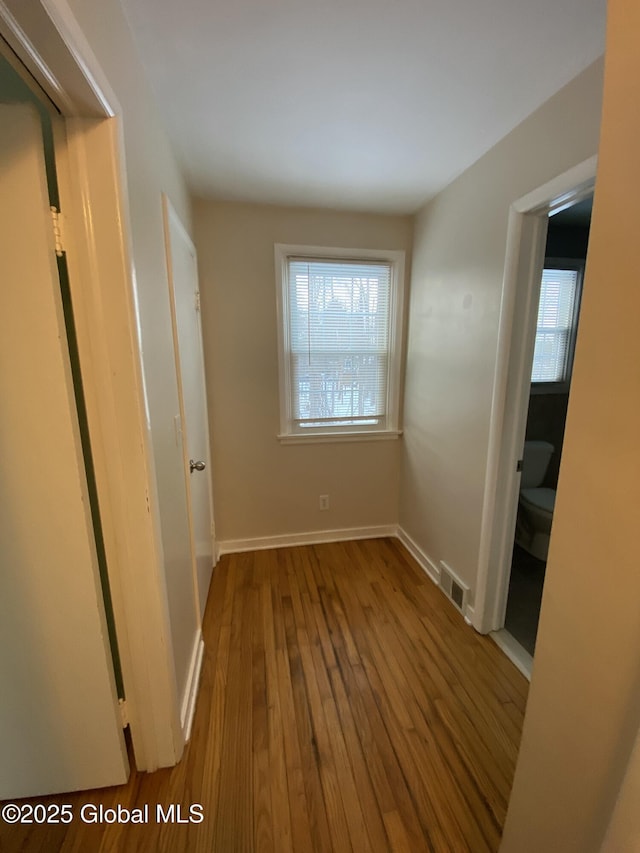 hallway featuring visible vents, baseboards, and hardwood / wood-style flooring