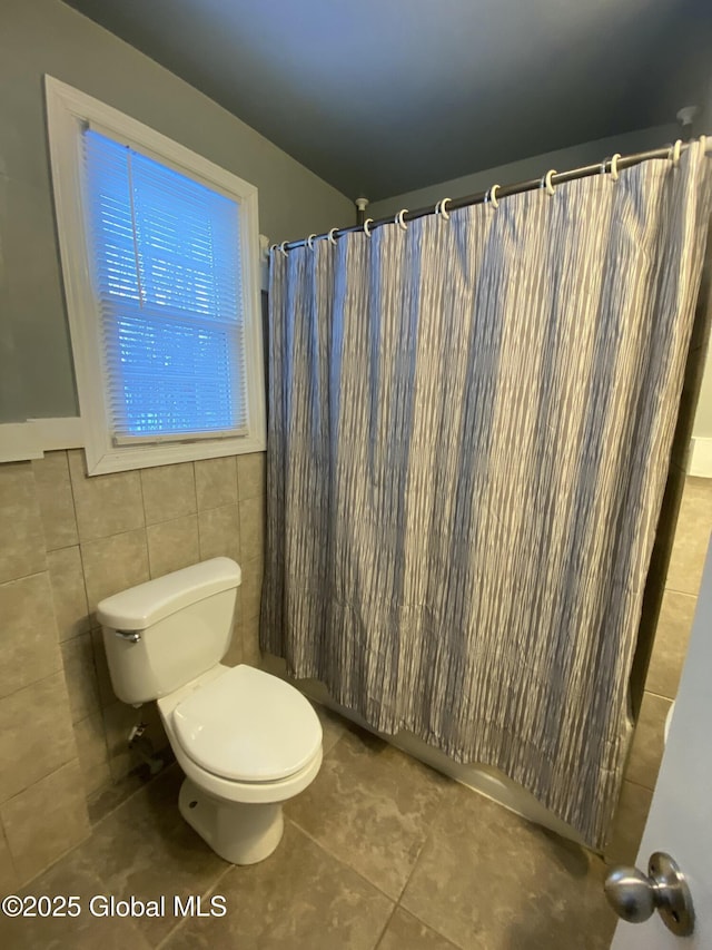 bathroom with toilet, a shower with curtain, tile walls, and tile patterned floors