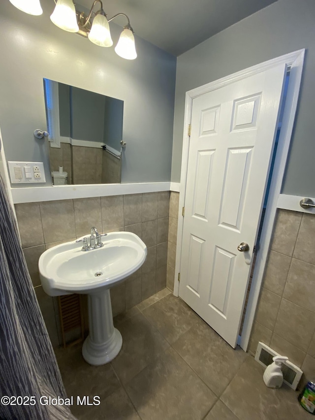 bathroom with visible vents, a notable chandelier, tile walls, and tile patterned floors