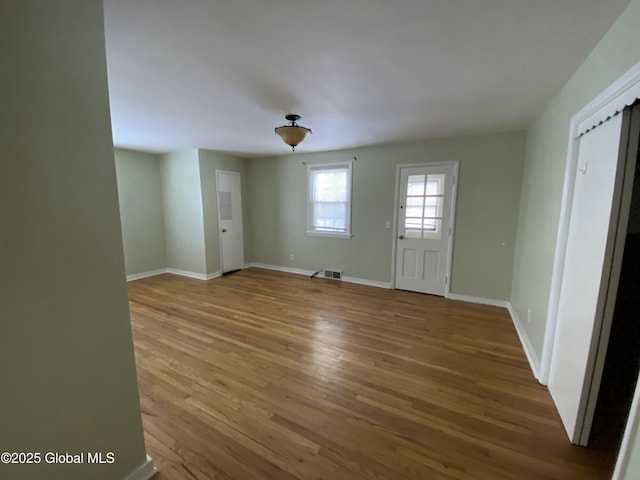 interior space featuring baseboards, visible vents, and wood finished floors